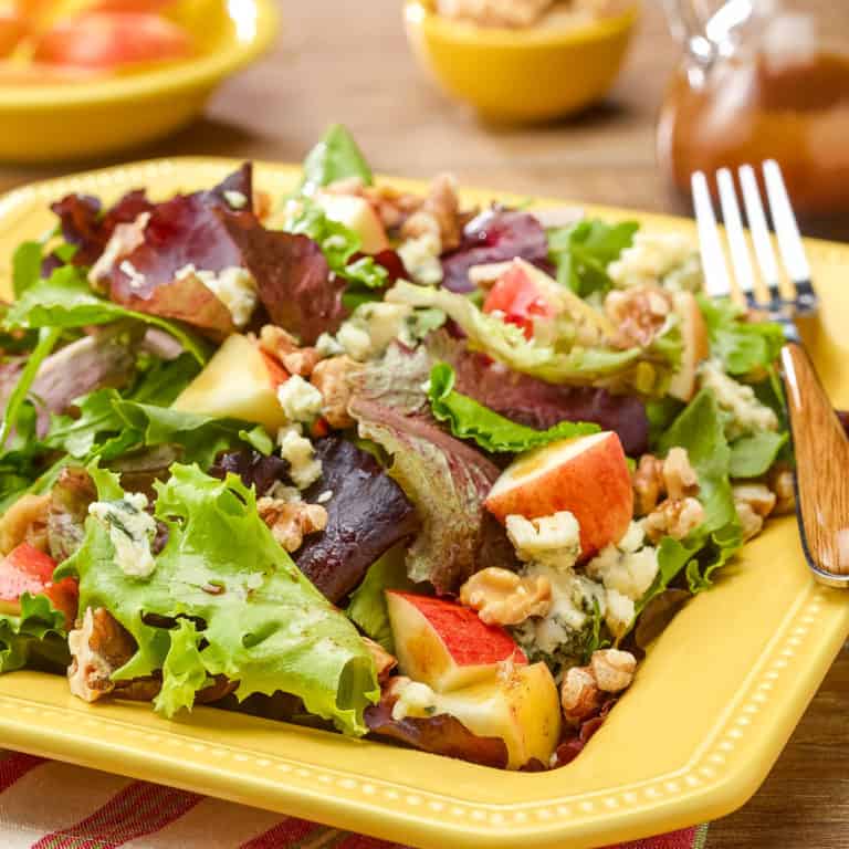 Square plate showing a generous portion of Mixed Green Salad with Apples, Walnuts and Stilton Cheese
