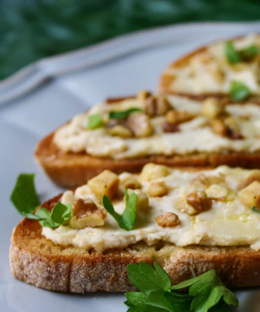 portions of 3 bruschetta topped with bean puree, on a blue plate