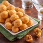 white platter holding Olive Cheese Balls, in front of two martinis