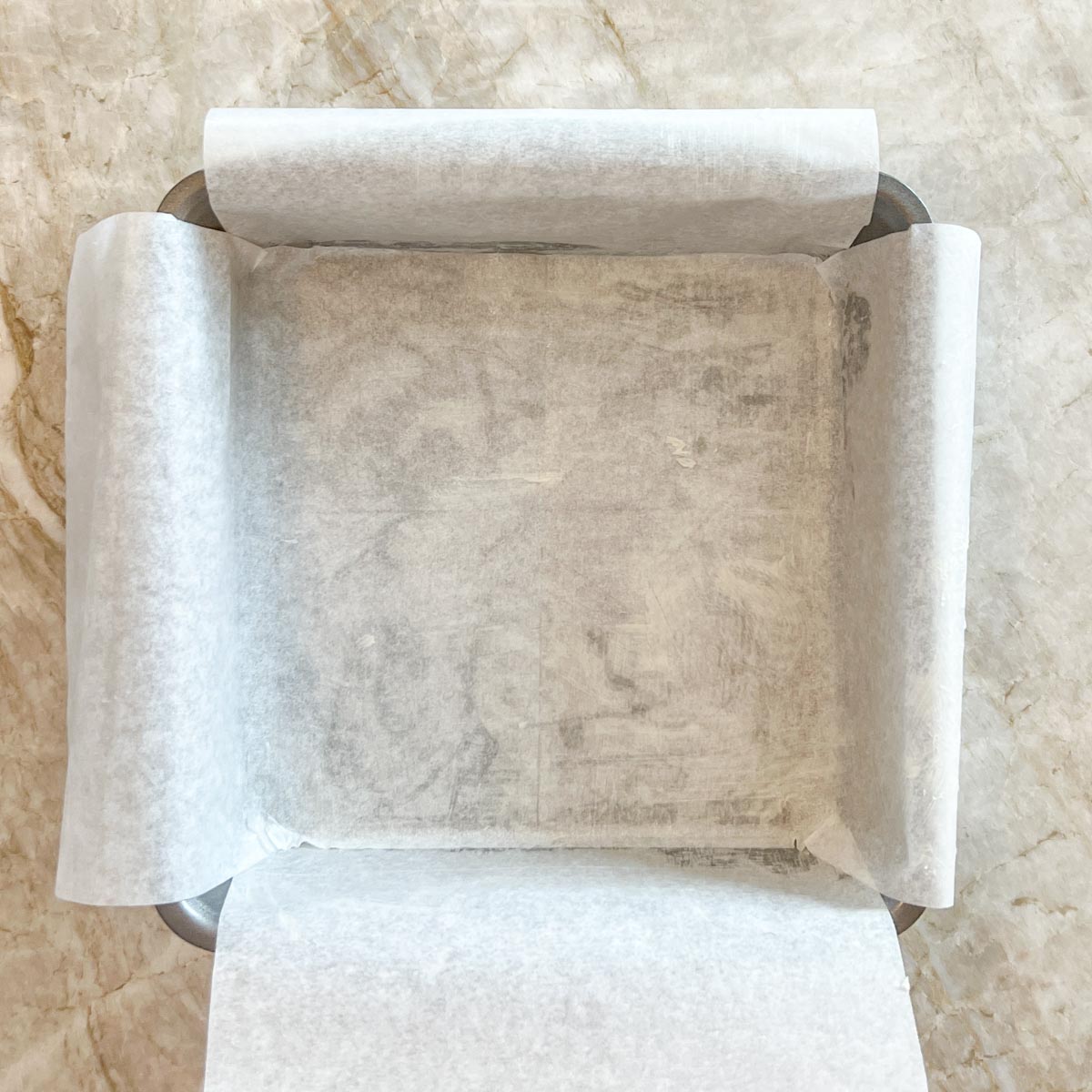 Showing how to line baking dish with parchment paper that's buttered and floured