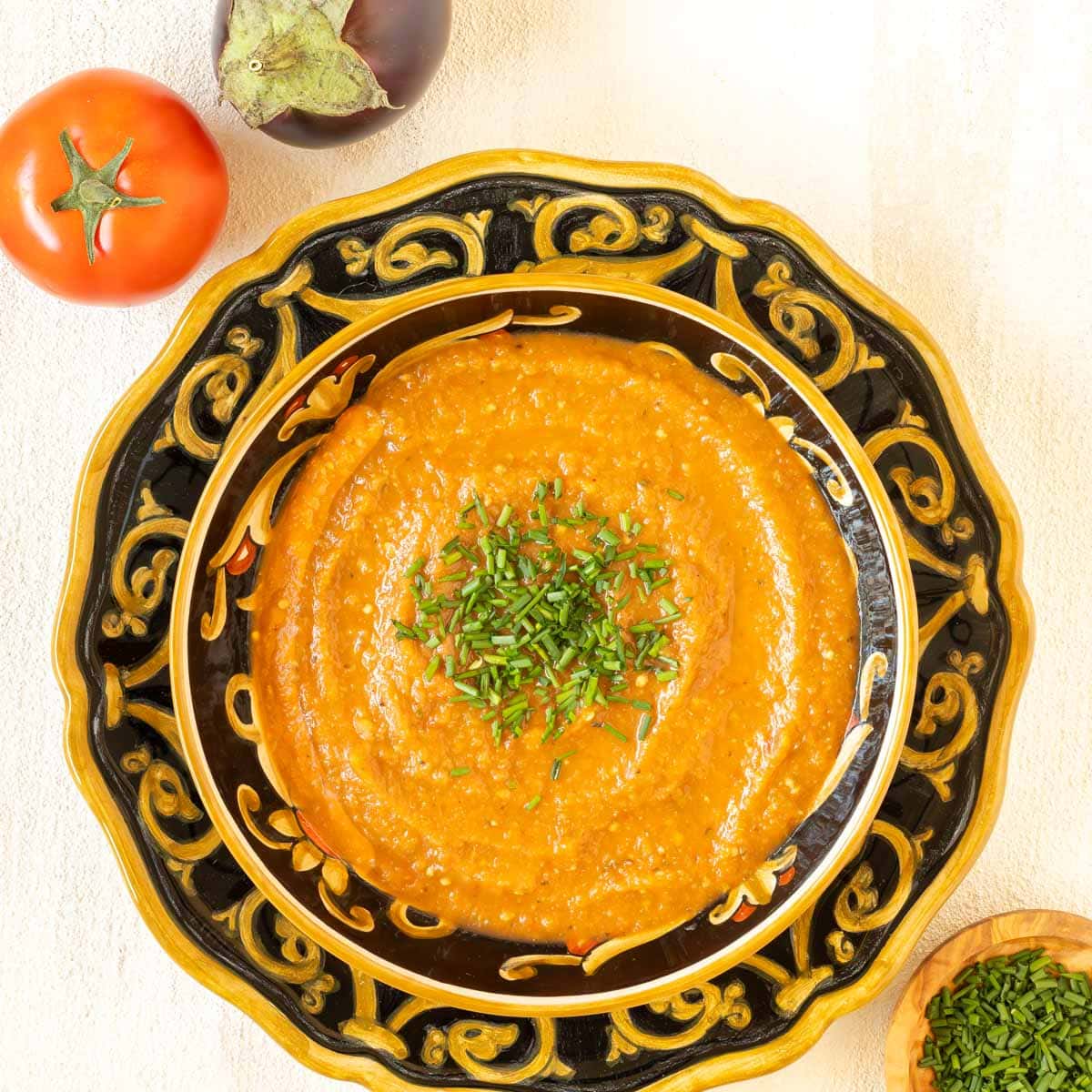 Closer overhead view of a bowl holding a portion of Roasted Eggplant Soup garnished with chives