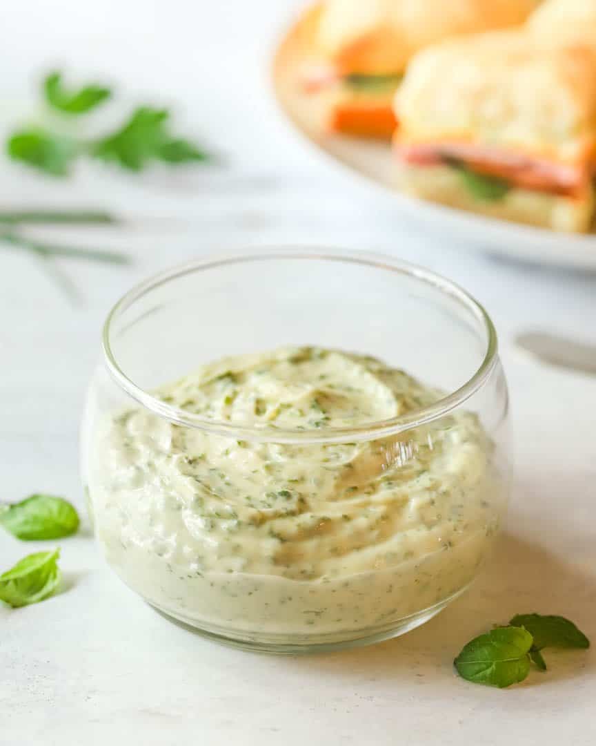 small glass bowl holding Herb Mayo with ham and cheese biscuits in the background