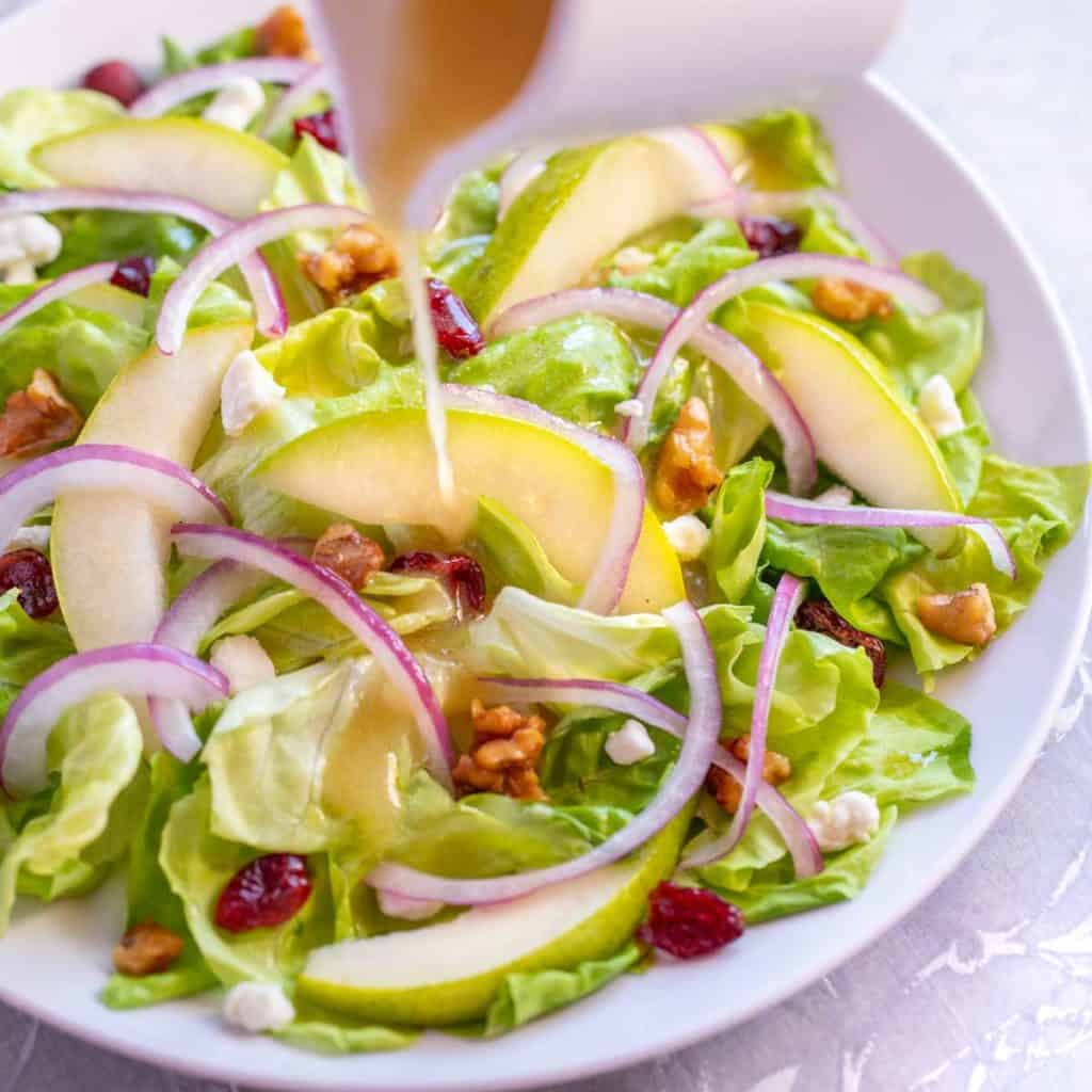 Pear and Goat Cheese Salad with Walnut Vinaigrette pouring out of a white pitcher
