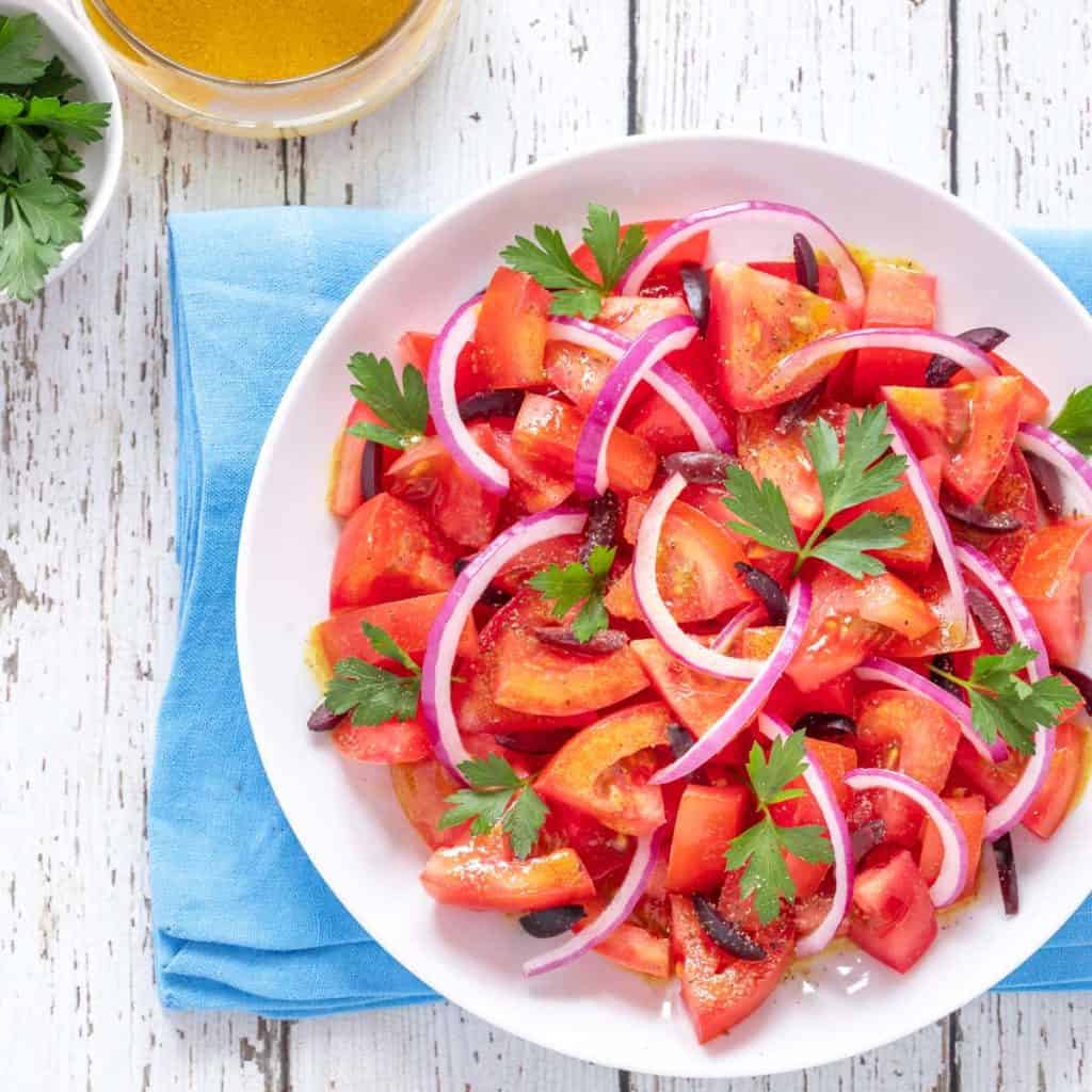 Close up of tomato salad garnished with red onion and parsley